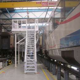 Plateforme d'accès et escaliers pour travailler sur les toits de voitures de voyageurs dans un atelier.