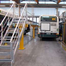 Adjustable walkway platform with stairs used for bus maintenance.