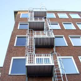 Kooiladders en balkons die worden gebruikt voor de evacuatie van een middelhoog flatgebouw.