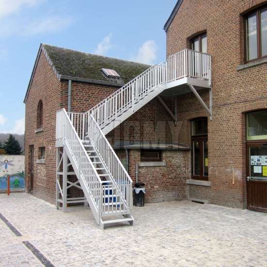 Buiten metalen trap met overloop gebruikt voor toegang tot een bakstenen school van één verdieping.