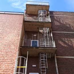 Window fire escape cage ladders and pass-through concrete access balconies.