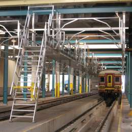 Walkway platform and shipladder used to access train rooftops for maintenance purposes in a workshop.