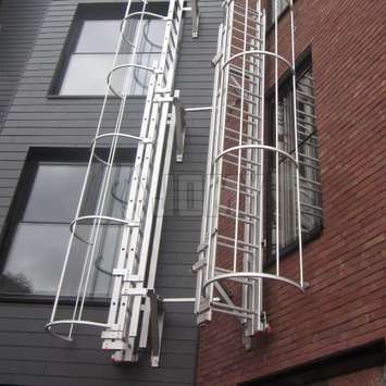 Drop-down ladder perpendicular to wall with a cage for fire evacuation.