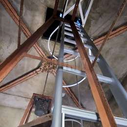 Echelle à crinoline pour l'accès à un trou d'homme dans un clocher d'église et installée à distance du mur avec des fixations spéciales.