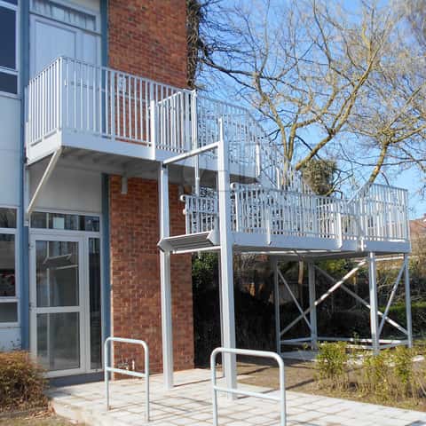 Escalier à volée relevable anti-intrusion, installé dans une cours d'école.