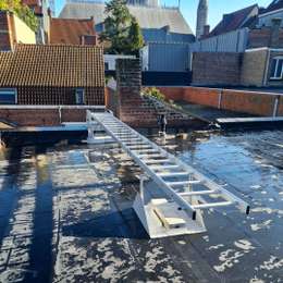 Rooftop fire escape gliding ladder that can be hidden on the roof and lowered to get down to safety from the roof of a city home.