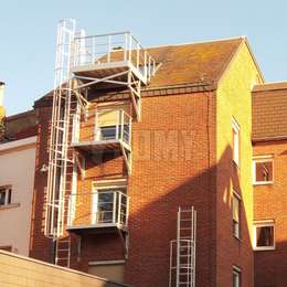 Fire escape platforms and cage ladder at the back of an apartment building.