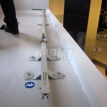 Horizontal lifeline rail on the edge of a roof for individual fall protection.