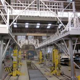 Drive-through industrial platform for accessing train carriage roofs in a railway workshop.