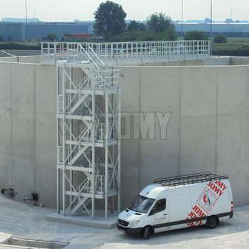 3 verdiepingen tellende industriële trap en platform voor toegang tot een betonnen opslagtank.