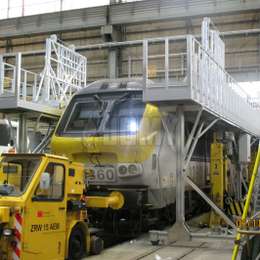 Mobile working platforms with access stairs for train maintenance at heights.