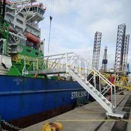 Beweegbare trappen en platform gebruikt om toegang te krijgen tot een afgemeerde boot in een scheepvaarthaven.