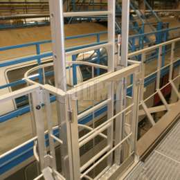 Opklapbare ladder met tegengewichten die wordt gebruikt om veilig toegang te krijgen tot werkplatforms in een treinwerkplaats.