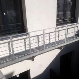 Passerelle en aluminium fixée au mur et servant de balcon d'évacuation incendie.