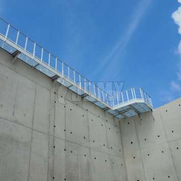 Passerelle industrielle en aluminium utilisée sur une cuve de stockage en béton.