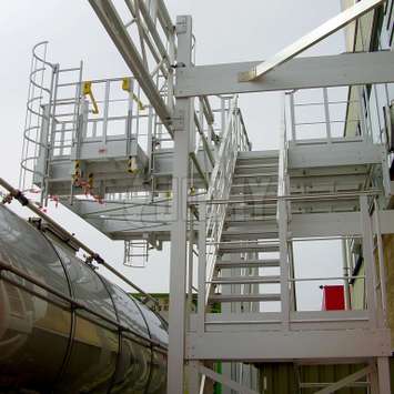 Platform toegankelijk via een trap, met toegangs kooiladders naar de mangaten boven de vrachtwagen tanks.