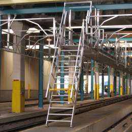 Industrial ship ladder for walkway platform access in a train maintenance workshop depot.