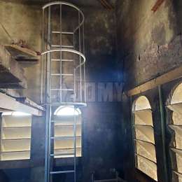 Cage ladder with side access to climb on a platform located in the bell tower of a church for maintenance.