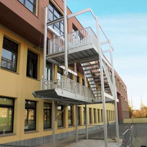 Fire evacuation stair with an anti-burglar retractable flight installed in a school courtyard.