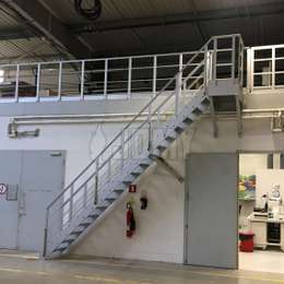 Toegangstrap voor een industriële mezzanine, met extra borstweringen als valbeveiliging.