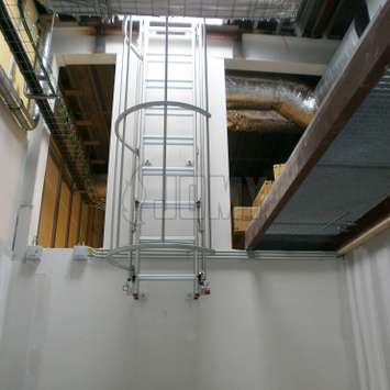 Uitschuifbare ladder met kooi in een industriële omgevingen.