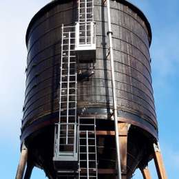 Vaste ladders met verticale reddingslijn en rustplatforms op een silo.