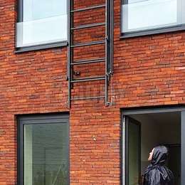 Venster evacuatie uitschuifbare ladder bevestigd aan een bakstenen muur.