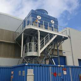 Walkway platform with stairs on tower structure for industrial machine maintenance.