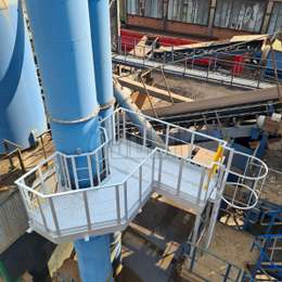 Work platform with access cage ladder on a shredder chimney for periodic emissions measurements.